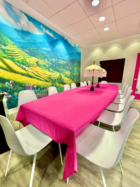 Meeting room with a large mural of a scenic landscape on the wall, pink tablecloth, and white chairs.